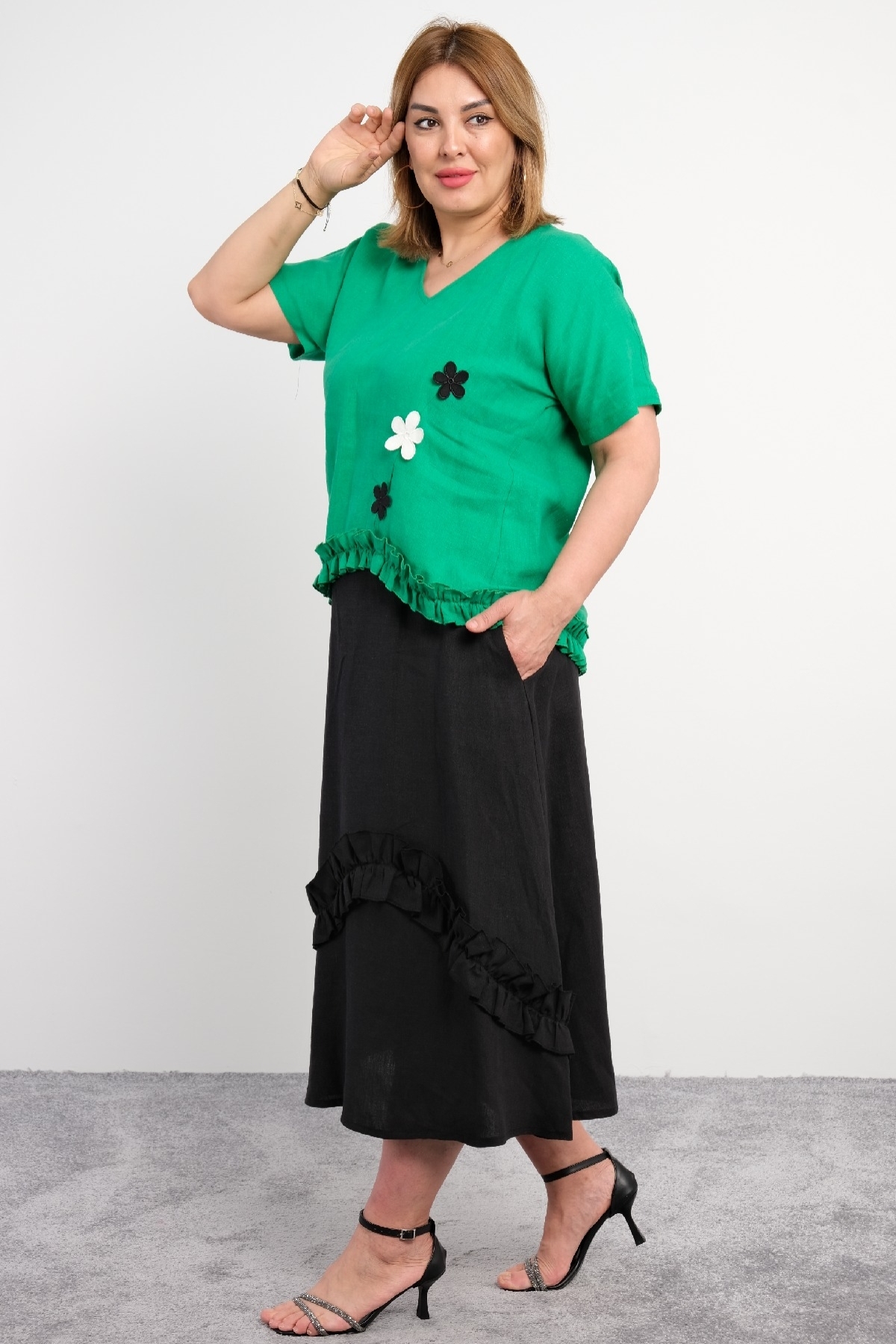  Two-piece suit for plus size women with ruffle details on the bottom, flower motifs, short sleeves, green color.