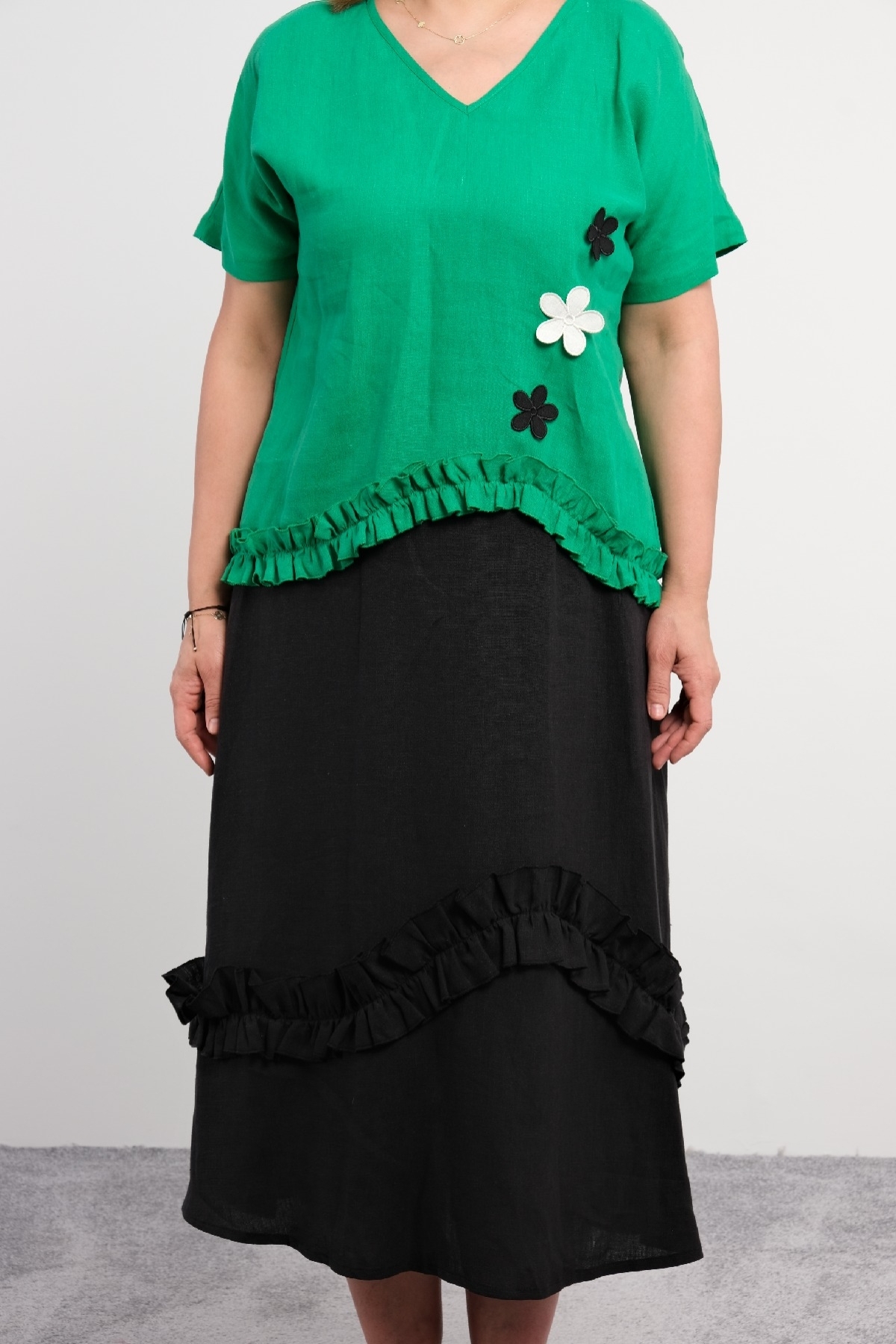  Two-piece suit for plus size women with ruffle details on the bottom, flower motifs, short sleeves, green color.