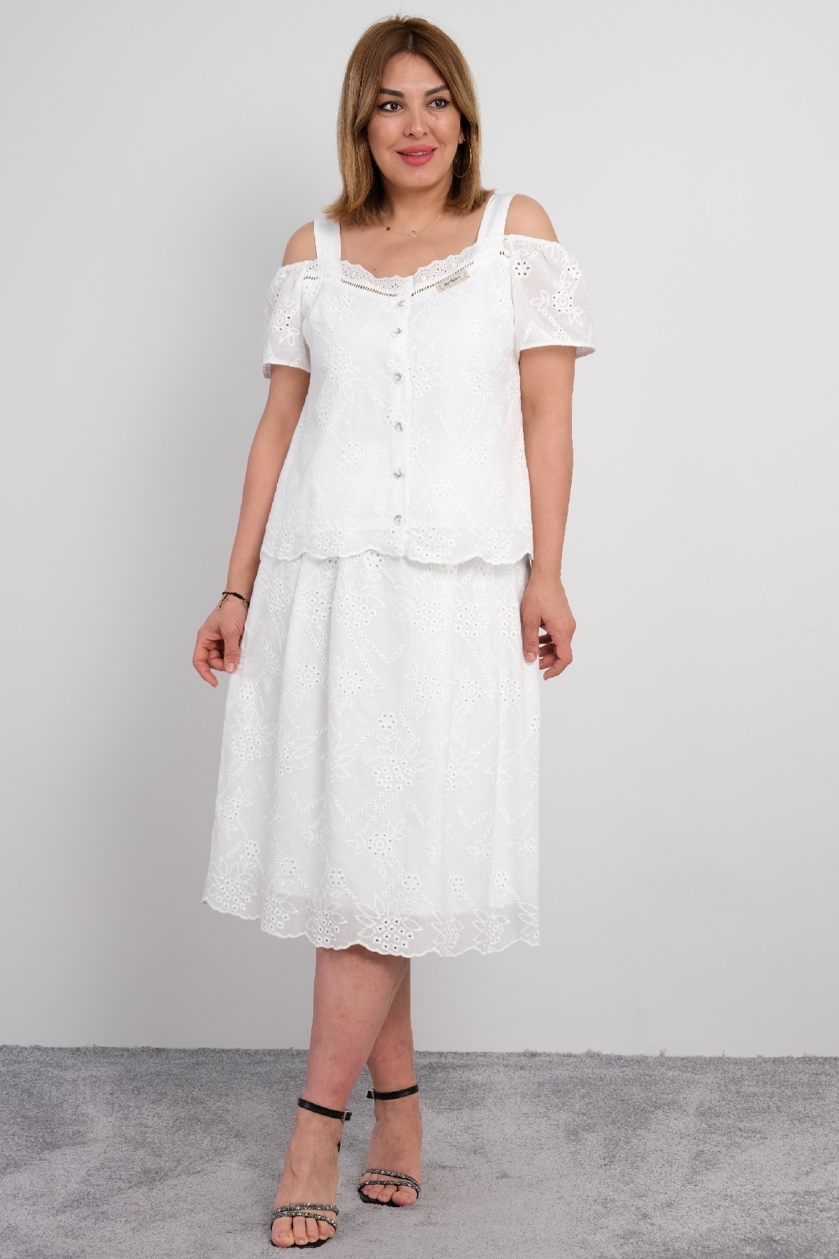  For plus size women, a two-piece suit consisting of a white colored, short-sleeved blouse with lace details and a long skirt.