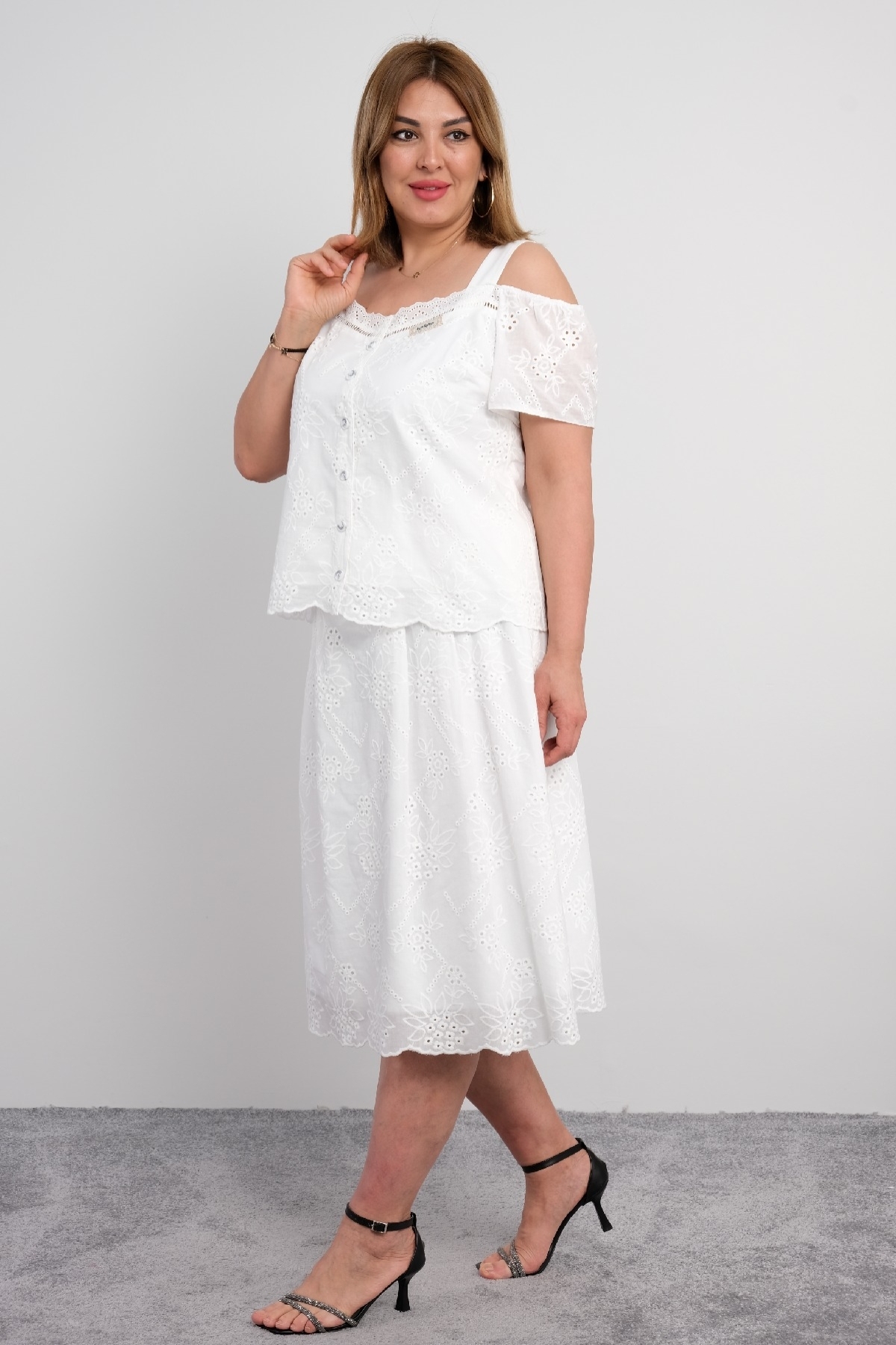  For plus size women, a two-piece suit consisting of a white colored, short-sleeved blouse with lace details and a long skirt.