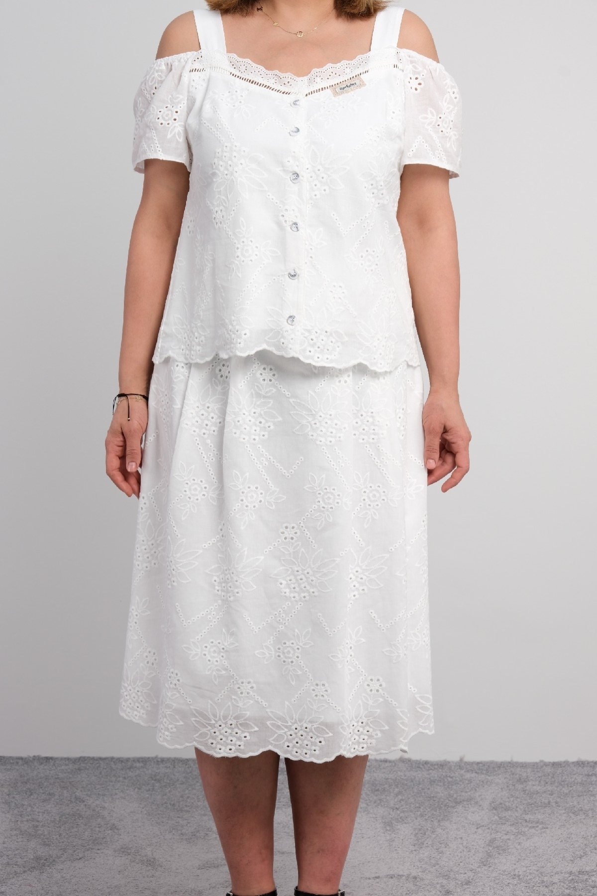  For plus size women, a two-piece suit consisting of a white colored, short-sleeved blouse with lace details and a long skirt.